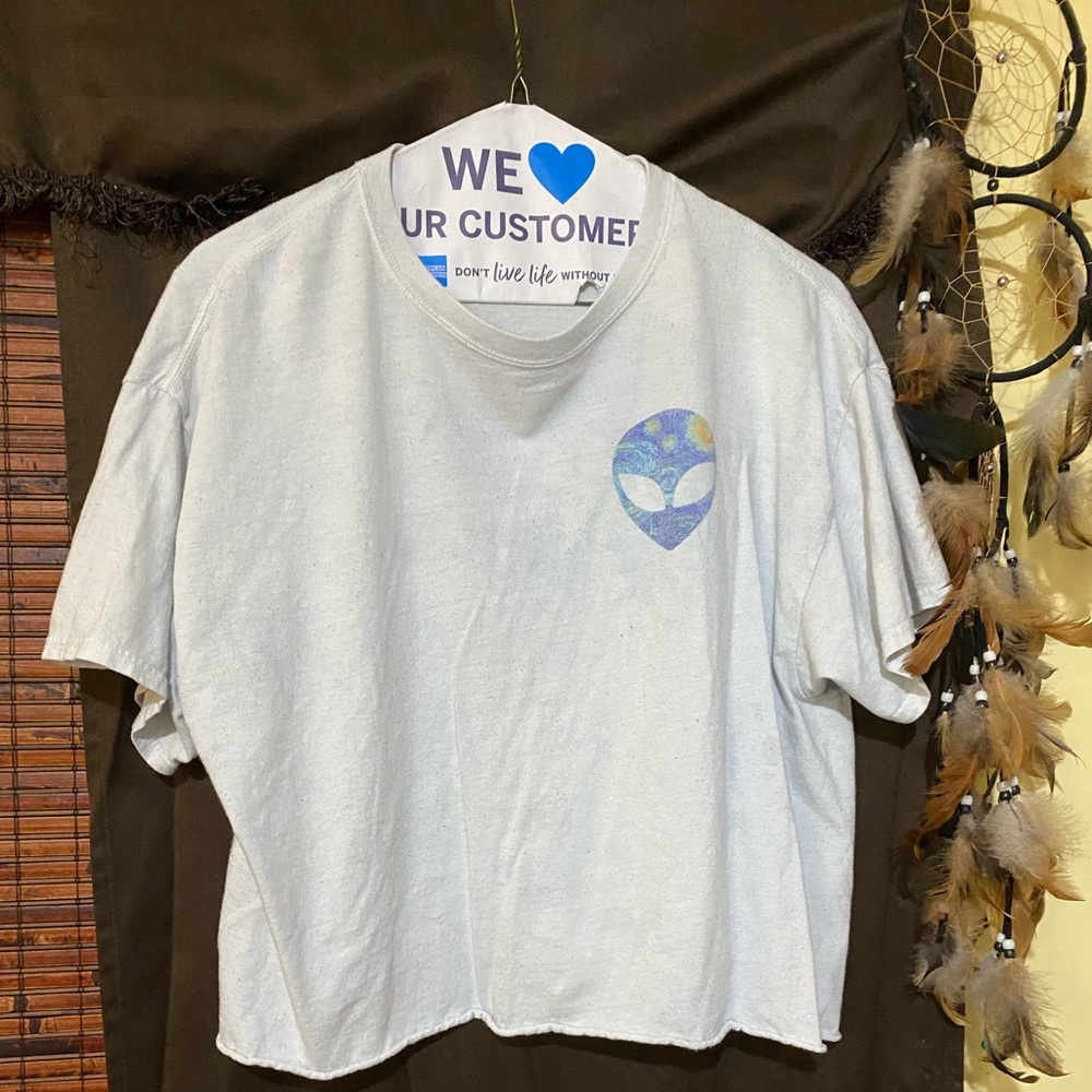 A cropped white tee with 2 alien faces on it